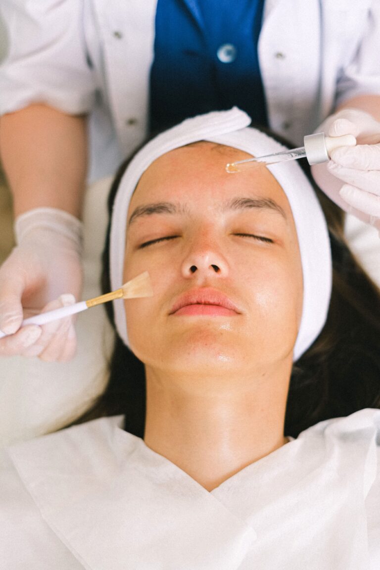 Kosmetyczka nakłada serum na twarz klientki podczas zabiegu w gabinecie beauty