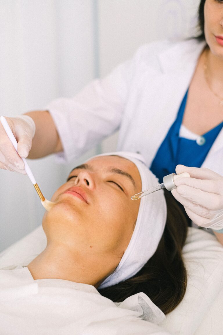 Konsultacja skóry w salonie beauty: kosmetyczka nakłada preparat na twarz klientki