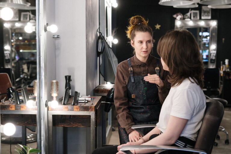 Stylistka rozmawia z klientką przy lustrze w salonie fryzjersko-beauty